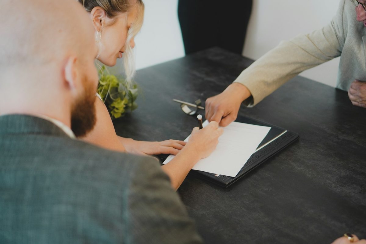 To personer signerer en avtale ved et skrivebord – les nedbetalingsavtalen nøye før du signerer