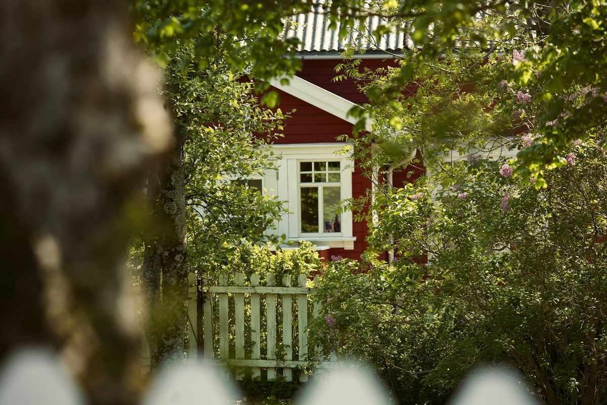 Rødt trehus med hvitt stakittgjerde – tvangssalg av bolig behandles av tingretten